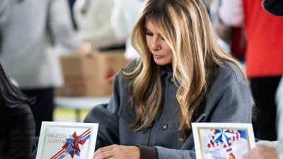 The First Lady signs a patriotic holiday greeting card during a Red Cross care-package event for service members.