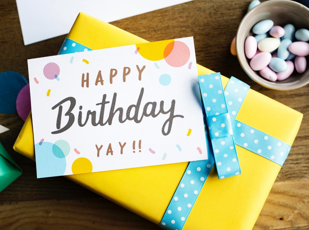 Birthday cards for business with colorful confetti design displayed on a wrapped gift