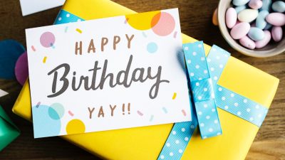 Birthday cards for business with colorful confetti design displayed on a wrapped gift